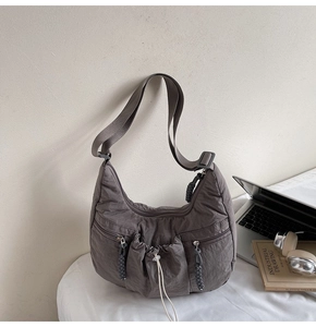 Detail of taupe pleated nylon hobo bag with drawstring pockets and wide shoulder strap