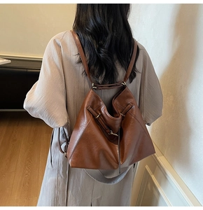 Brown leather backpack with triangle silhouette and gold hardware on model