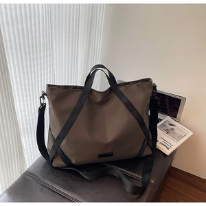 Nahaufnahme der braunen Reisetasche mit schwarzen Trägern auf einer Lederbank im Büro