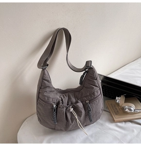 Close-up of a dark grey nylon pleated crescent bag featuring functional pockets and hardware
