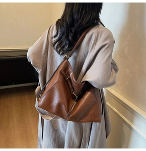 Detail of vintage brown leather tote bag with subtle lychee grain and metallic lock