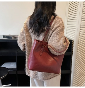 Deep burgundy leather tote bag styled on model showcasing sleek city fashion aesthetics