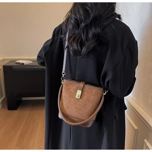 Detailed view of a brown bucket bag with diamond stitching and golden turn-lock