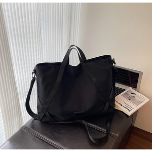 Detailansicht der großen schwarzen Reisetasche aus Nylon mit robusten Tragegriffen und Gurt