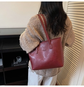 Detail of vintage dark red tote bag featuring natural leather texture and long shoulder straps