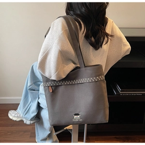 Detail of dark grey canvas tote bag featuring white zigzag stitching and cute embroidery