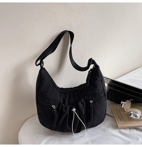 Macro detail of black pleated crescent bag with three pockets and adjustable shoulder strap