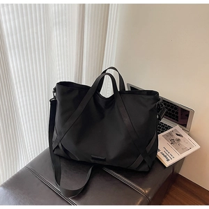 Nahaufnahme der schwarzen Nylon-Reisetasche mit breiten Tragegurten auf einer Lederbank