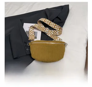 Detail of mustard yellow corduroy saddle bag with geometric woven strap and phone for scale