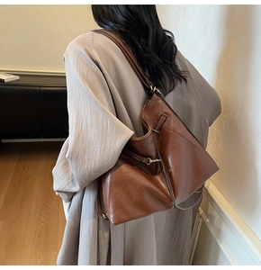 Brown large capacity leather shoulder bag with gold ring details on a female model