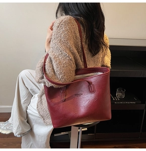 Detail of dark red tote bag with retro leather texture and embossed New York lettering