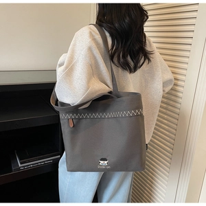 Detail of gray canvas tote bag with Docile-girl embroidery and zigzag stitching