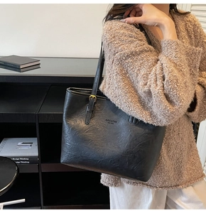 Detail of black leather tote bag with gold lettering and adjustable shoulder strap