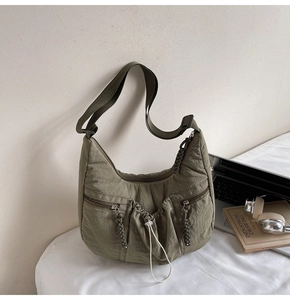 Close-up of olive green pleated nylon crossbody bag with dual pockets and drawstring detail