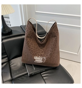 Detail of leopard print tote bag with embroidery on black leather seat with book decor