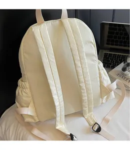 Detail view of the wide padded shoulder straps and breathable back of the cream canvas backpack
