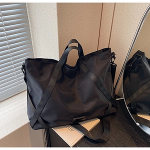Detail der schwarzen Nylon-Reisetasche mit Metallplakette, breitem Griff und Gurt