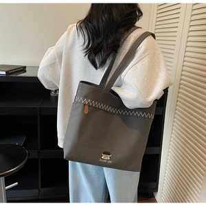 Detailed embroidery and contrast stitching on the grey canvas tote bag for daily use
