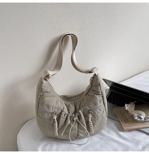 Sage green crescent bag with pleated nylon fabric and side zipper detail in casual setting