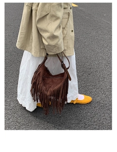 Dettaglio della borsa hobo in pelle scamosciata marrone scuro con lunghe frange e fibbie