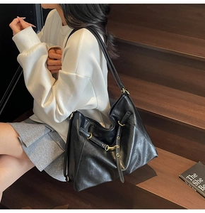 Detail of black soft leather tote bag with gold hardware on wooden stairs scene