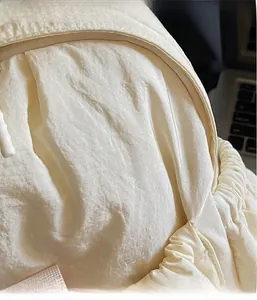 Close-up of off-white lightweight nylon backpack with fine wrinkle texture and sturdy handle