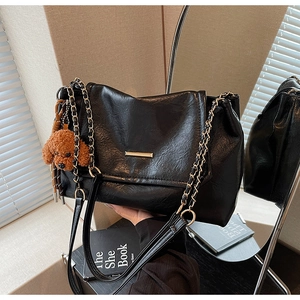 Detail of black textured PU shoulder bag with gold chain strap and cute bear charm