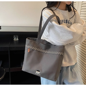 Detail of grey canvas tote bag with contrast stitching and cute cartoon embroidery