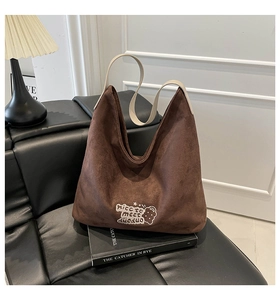 Detail of vintage brown suede hobo bag with contrast cream leather strap and graphic print