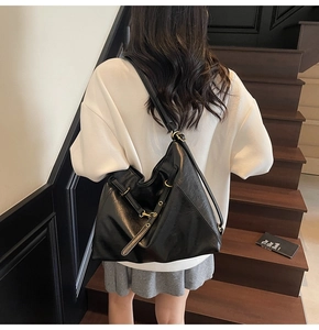 Detailed view of the large black leather tote bag with gold hardware worn by a model