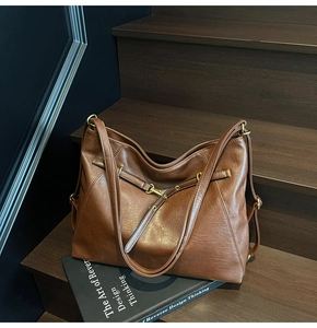 Close-up of vintage brown PU leather texture and decorative buckle on tote bag