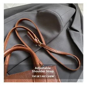 Detail showing the adjustable leather shoulder strap with vintage golden buckle