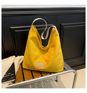 Detailed macro view of yellow suede hobo bag with nice to meet you embroidery