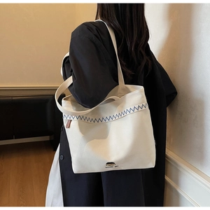 Detail of minimalist canvas tote bag featuring blue stitching and Docile girl print