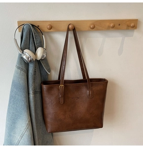 Detail of vintage brown leather tote bag showing metallic buckles and fashion logo text