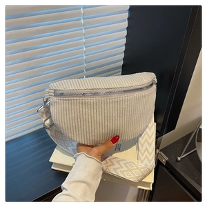 Detail of cream corduroy saddle bag featuring a geometric patterned wide crossbody strap
