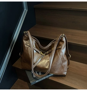 Detail of vintage dark brown faux leather tote bag with double straps on wooden stairs
