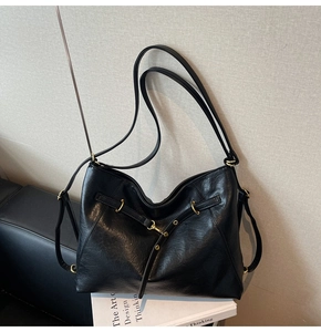 Close-up of black pebble leather tote bag featuring elegant gold hardware details