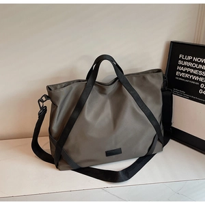 Detail der salbeigrünen Reisetasche aus Nylon mit schwarzen Trageriemen und Leder-Patch