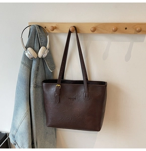 Close-up of vintage brown tote bag with adjustable straps and fashion text detail