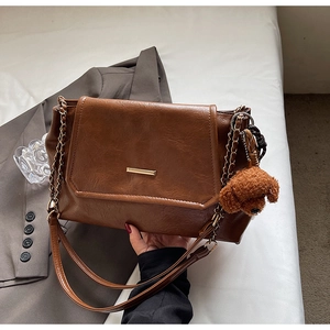 Brown retro flap crossbody bag with gold hardware and a cute puppy plush charm detail