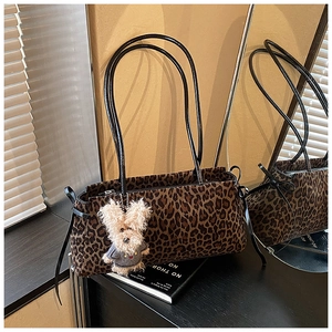 Detalle de bolso con estampado de leopardo, correas de cuero negro y colgante peluche