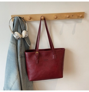 Detailed macro view of burgundy leather tote bag with lychee texture and fashion lettering