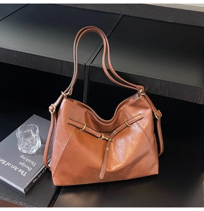 Macro detail of the brown hobo bag featuring natural crinkled texture and gold metal buckle