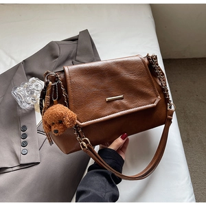 Detailed view of brown PU leather shoulder bag with gold chain and teddy bear charm