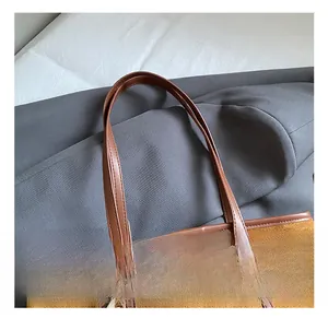 Dettaglio del manico in pelle marrone di una borsa tote gialla in similpelle scamosciata