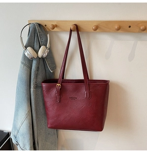 Detail view of deep red tote bag with pebble leather texture and NEW YORK branding
