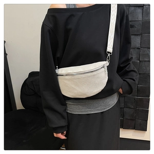 Detailed close-up of white corduroy texture and woven wide strap on a crossbody saddle bag