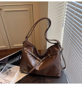 Detail view of large dark brown leather tote bag with gold eyelets and natural shadows