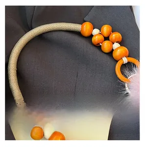 Détail d'une anse de sac en perles orange avec un pompon décoratif en fausse fourrure
